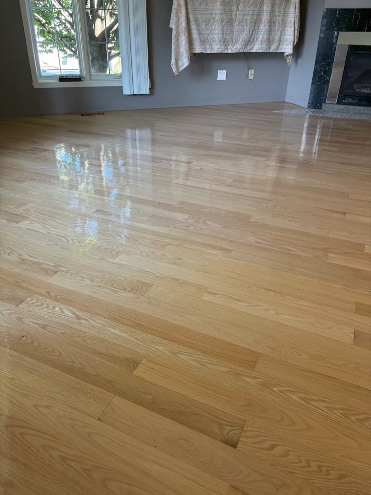 Glossy refinished oak floor beside a fireplace